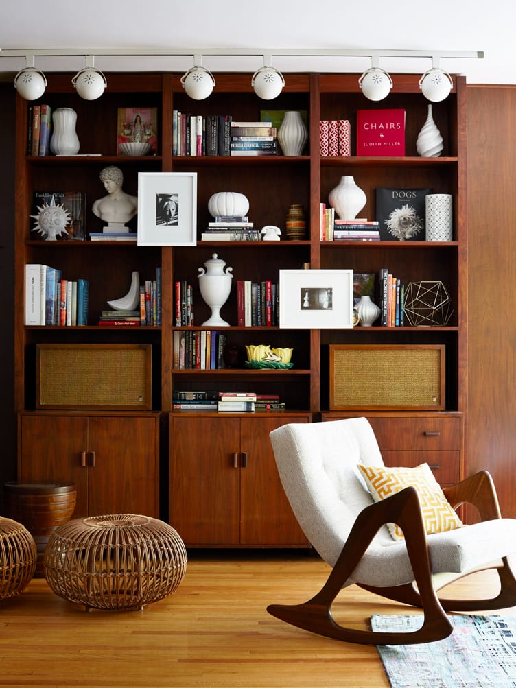 Wood bookshelves with wicker ottoman and gray upholstered rocking chair