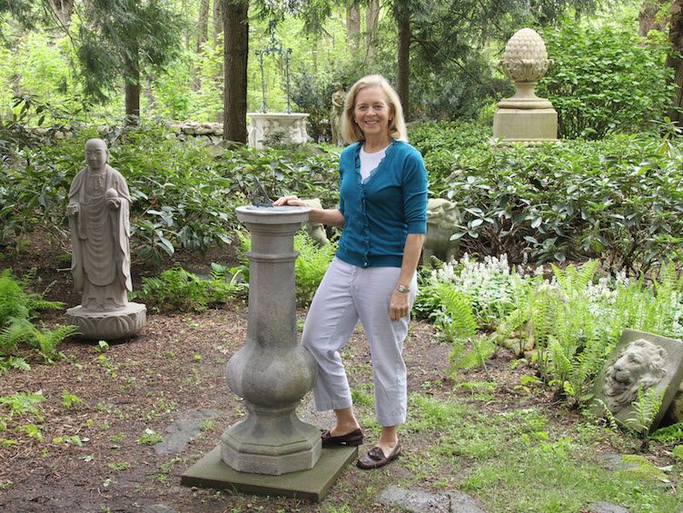 Barbara Israel of Barbara Israel Garden Antiques poses with large stone pedestal 