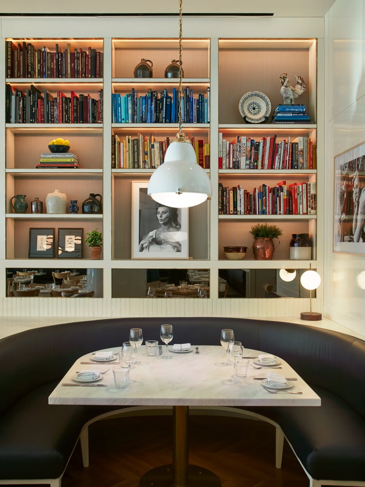 Chiara deRege interior design marble dining table with black leather wrap around bench and color coordinated bookshelves
