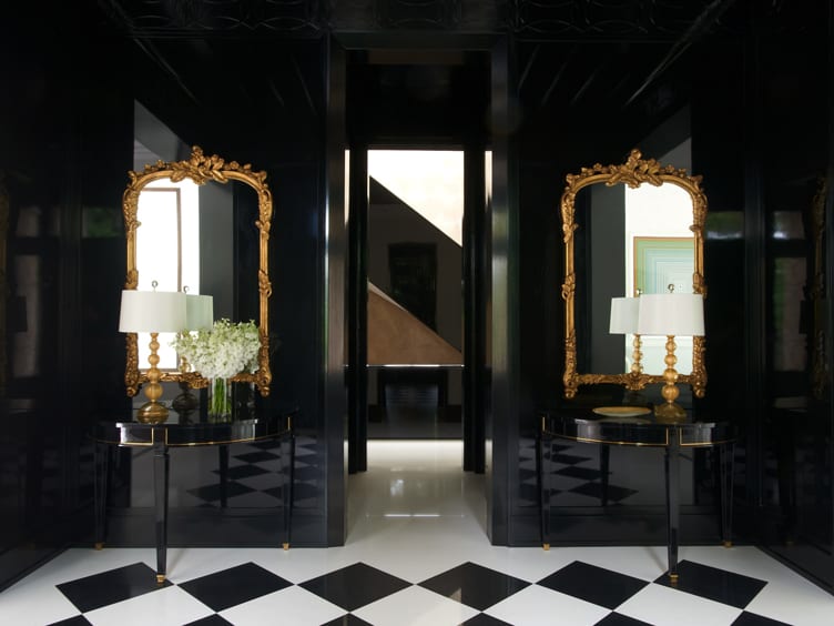 Hall with marble checkerboard floor, glossy black walls, and twin gold mirrors