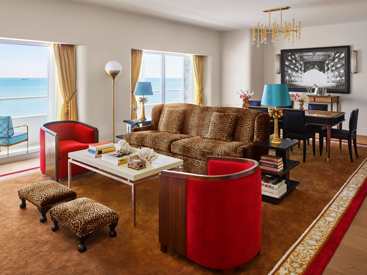 Living and dining room with cheetah couch, red accent chairs, and large  rug.