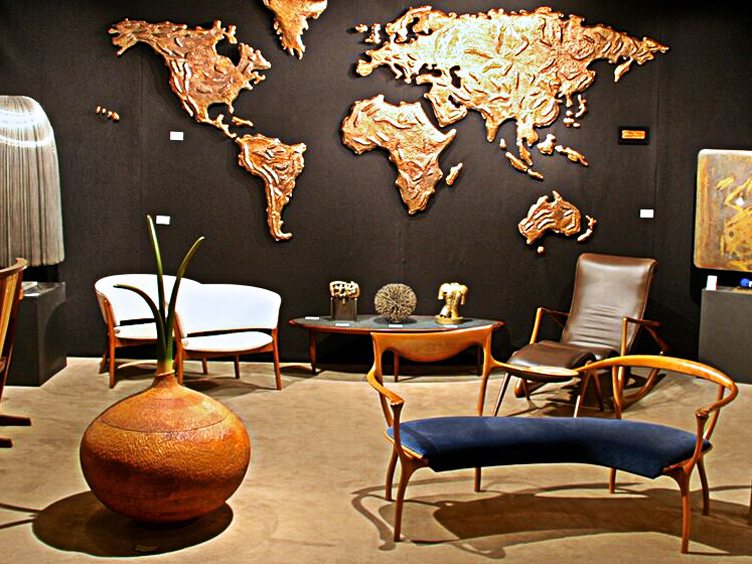 Lost City Arts show room with mid-century wood furniture and gold map wall sculpture 