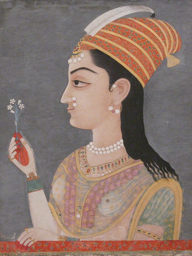Portrait of a South Asian woman, wearing a tikka, an ornament suspended from a string of pearls, and a nath or nose ring.