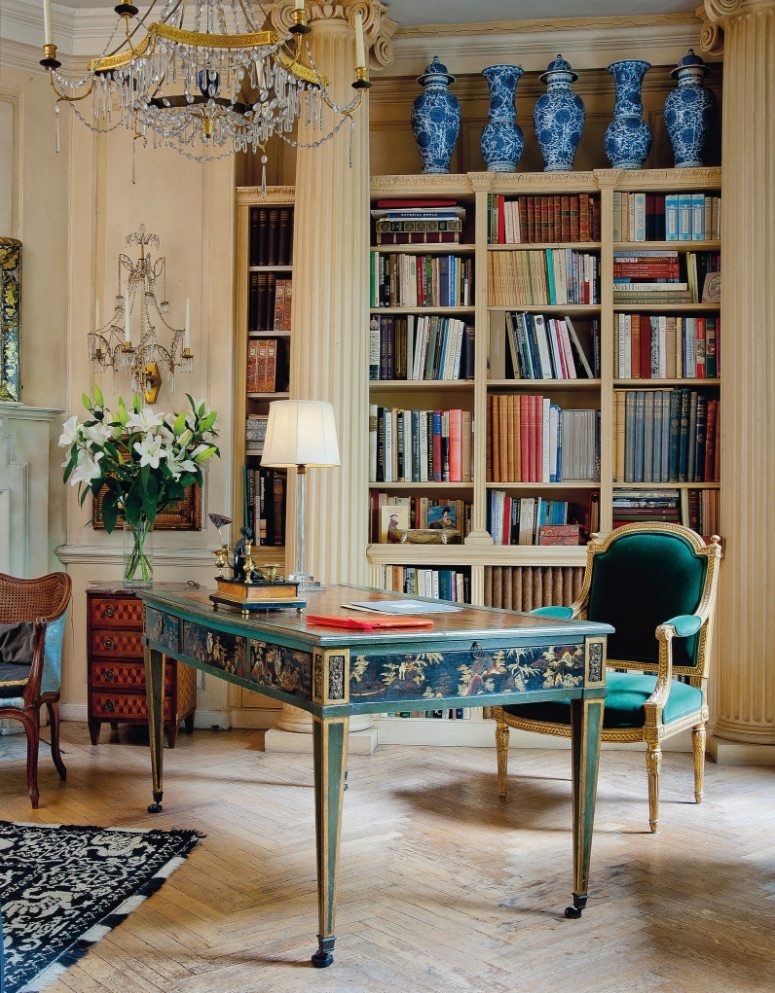 Library with teal victoria-press desk and matching velvet chair, blue and white china vases, and gold-trimmed chandelier.