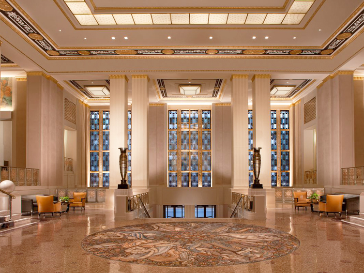 Lobby with grand marble floors, columns, and blue stained glass.